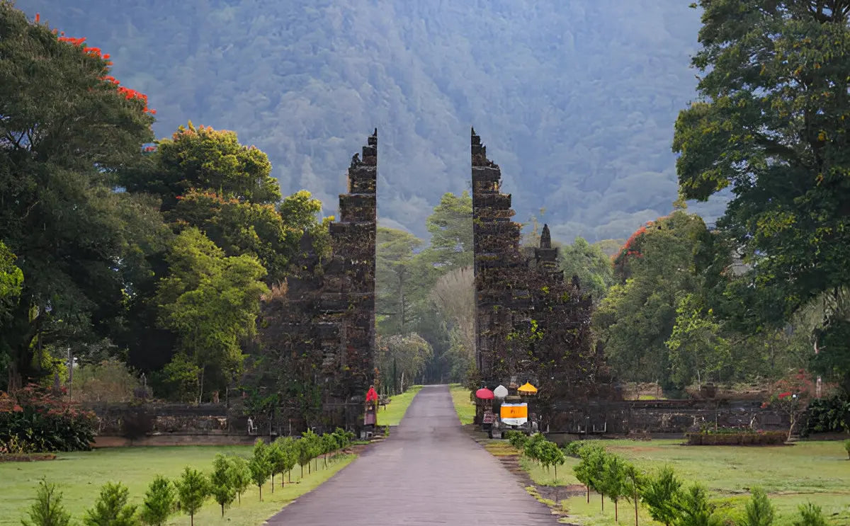A view of Bali's iconic Gate of Heaven, framed by vibrant greenery and distant mountains, offering a serene and picturesque scene.