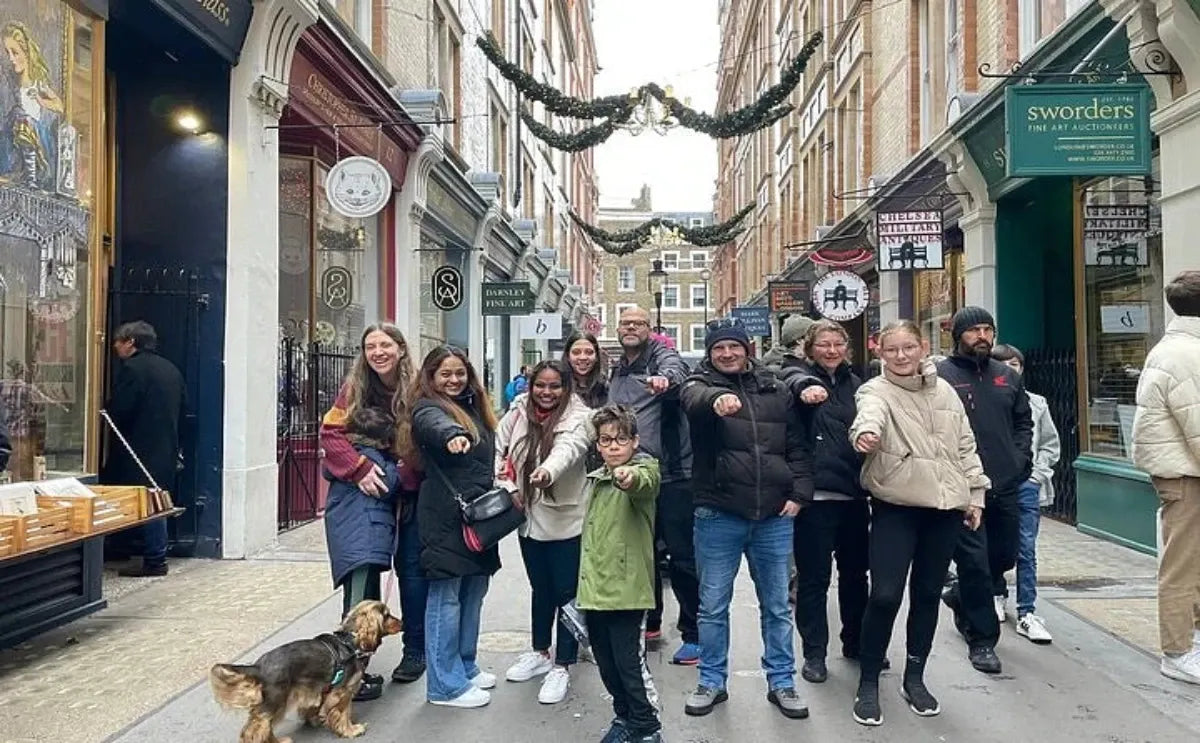 A group of Harry Potter fans enthusiastically posing with wands in hand, standing in a vibrant London street known for its connection to the wizarding world.