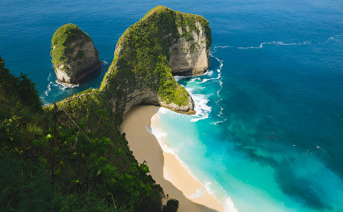 Aerial view of Kelingking Beach in Nusa Penida, Bali, showcasing its iconic T-Rex-shaped cliff, turquoise waters, and secluded sandy shore.