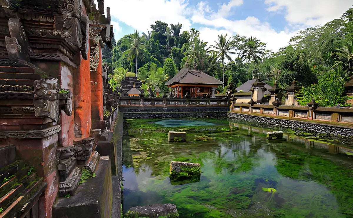 Scenic view of a sacred temple surrounded by lush greenery and a serene pond, part of Bali's cultural and spiritual heritage.