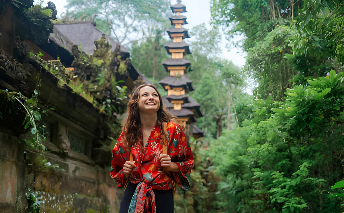 Visitor smiling while exploring the lush green pathways and traditional temple architecture at Bali's Monkey Forest Sanctuary."