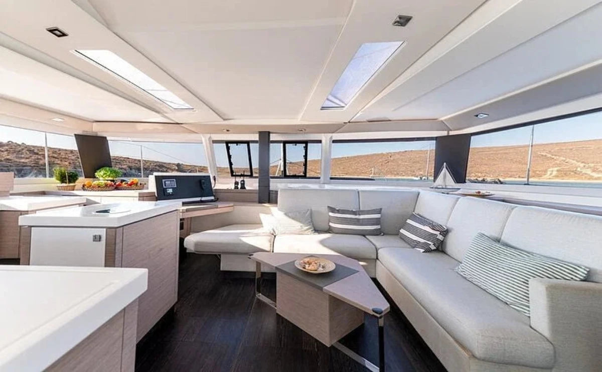 The spacious interior of the "White Coral" catamaran, featuring modern seating, a sleek kitchen, and panoramic windows offering stunning sea views.