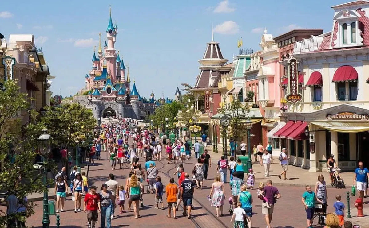 Visitors stroll down Main Street., leading to the iconic Sleeping Beauty Castle at Disneyland Paris, surrounded by charming shops and lively atmosphere.