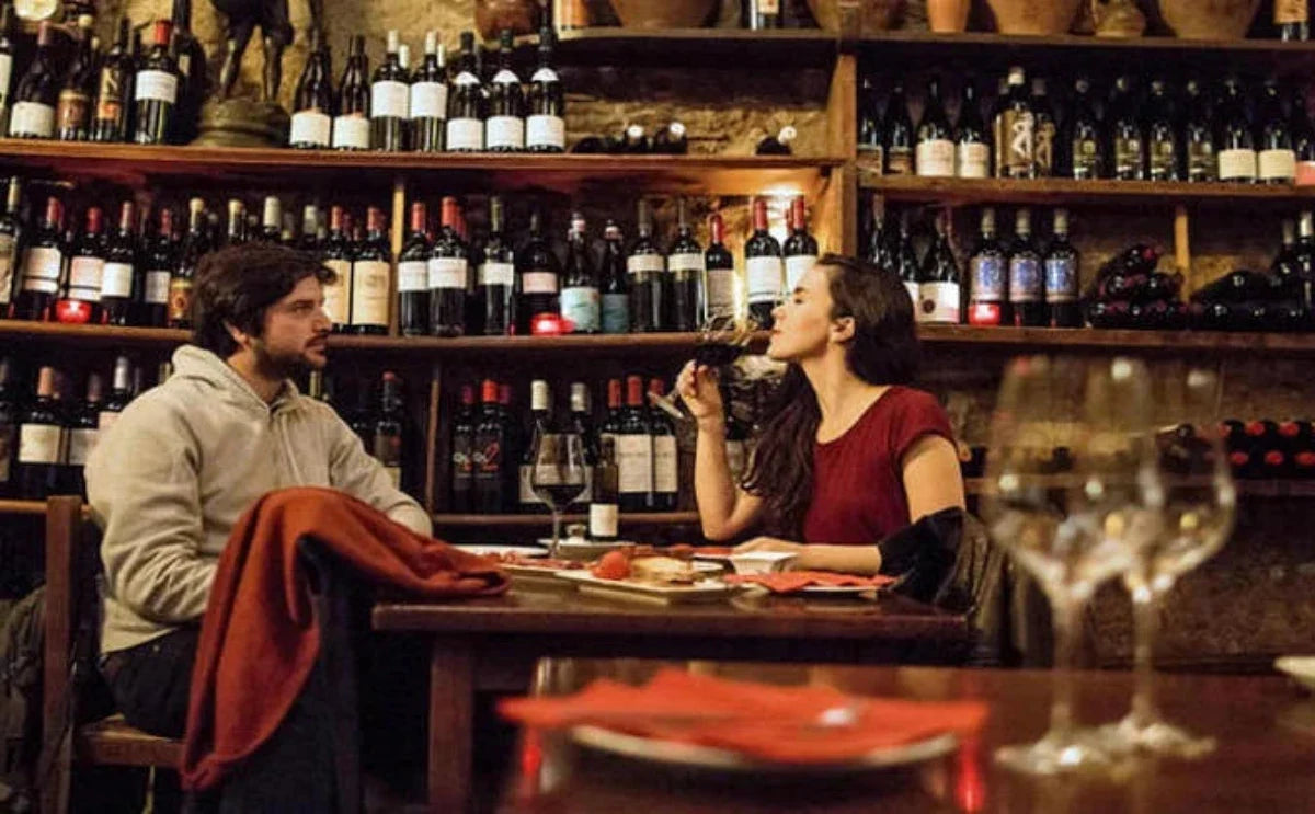 A cozy wine bar in Barcelona, where a couple enjoys tasting regional wines surrounded by shelves of bottles and a warm ambiance.