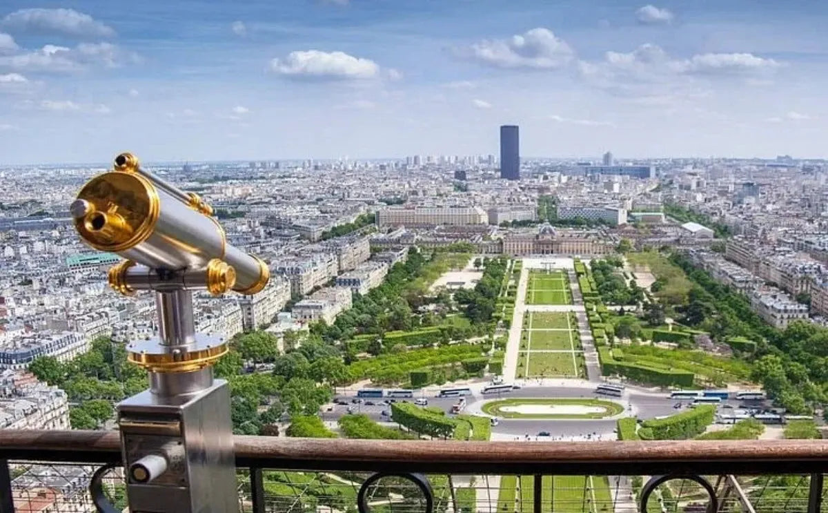 View of Paris from the Eiffel Tower, featuring a telescope and the Champ de Mars below.