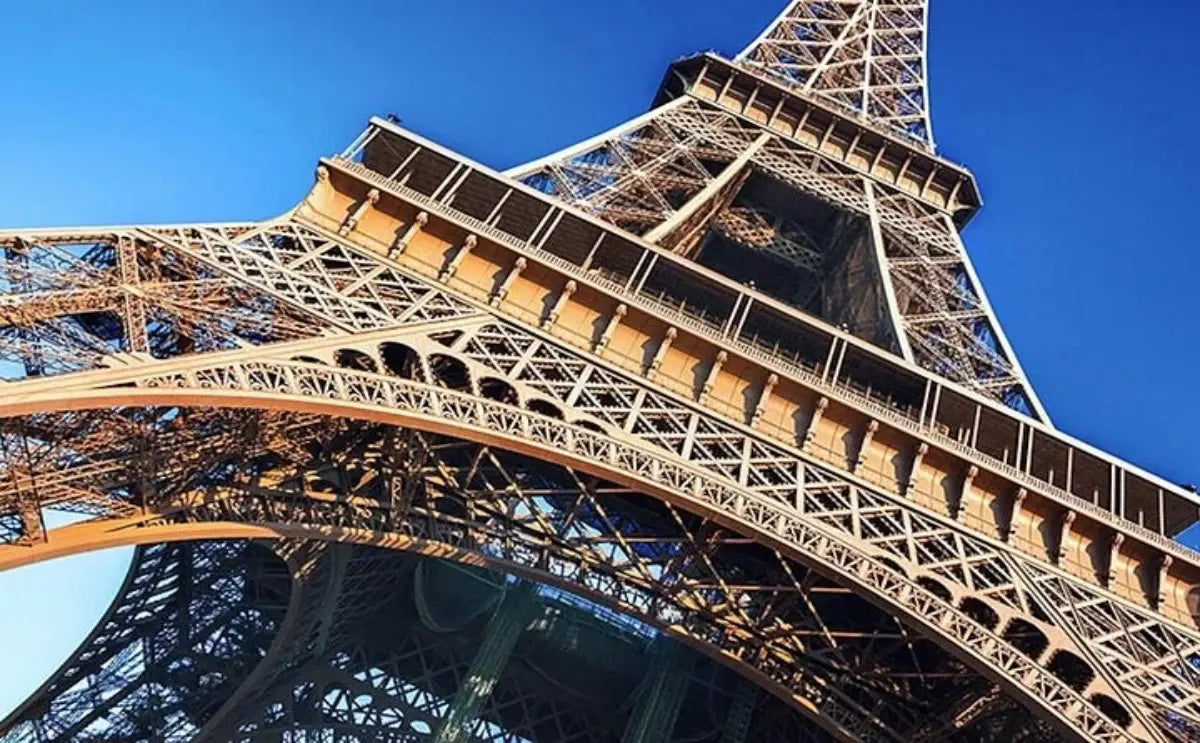 Close-up view of the Eiffel Tower's intricate iron structure against a clear blue sky.