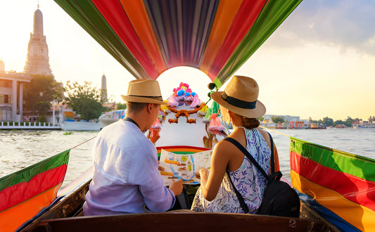 A charming couple enjoying a romantic tour on a longtail boat along the Chao Phraya River, with Wat Arun's iconic spires in the background, during their sightseeing adventure in Bangkok, Thailand.