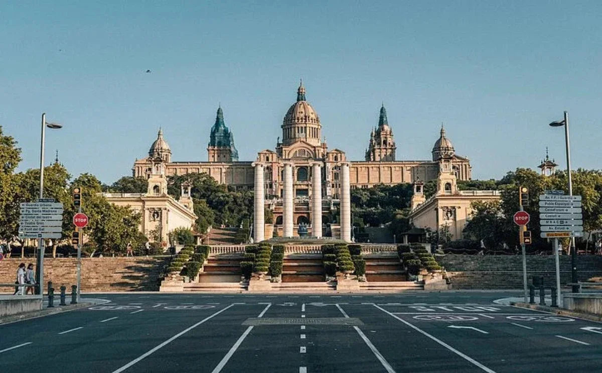 This is the grand entrance to the National Art Museum of Catalonia in Barcelona, with its impressive architecture and cascading steps leading to the museum. The surrounding area adds a touch of elegance with its greenery and symmetrical design.