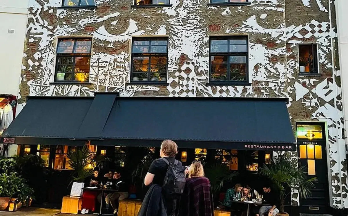 A person standing outside a colorful building in Notting Hill with unique wall art and large windows.