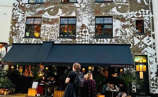 A person standing outside a colorful building in Notting Hill with unique wall art and large windows.