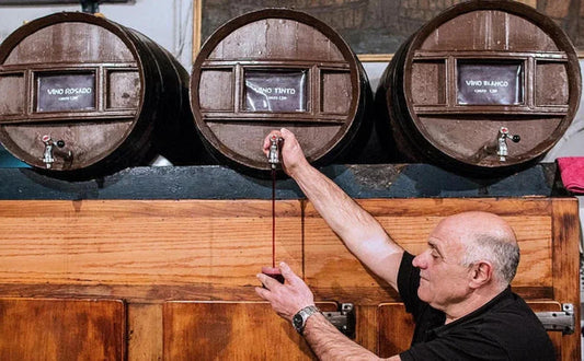 A man pours wine directly from a barrel during a tapas and wine tour in Barcelona, showcasing the authentic experience of traditional Catalan drinks.